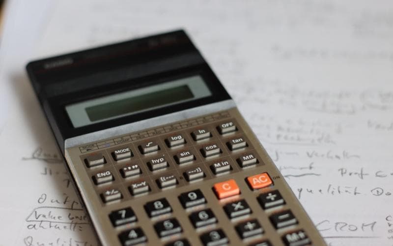 A scientific calculator resting on a page of handwritten working