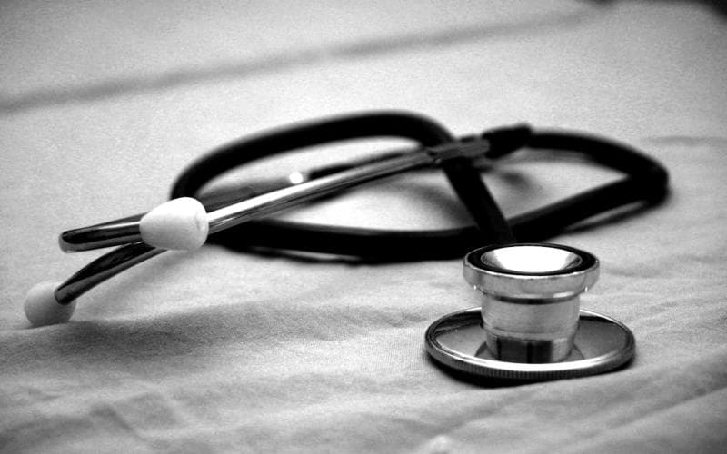 A stethoscope resting on a hospital bed sheet