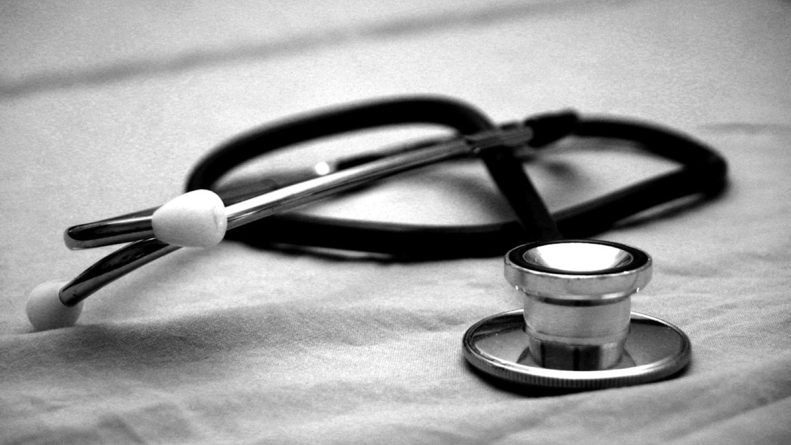 A stethoscope resting on a hospital bed sheet